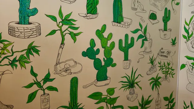 Mural of green cacti and plants growing from quirky line-drawn objects like a frying pan, snorkel mask, and beer can