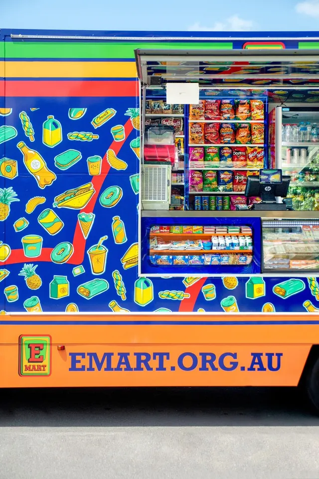 Mobile store vehicle wrap featuring bold graphic illustrations of snacks, fruit, and drinks on a blue background