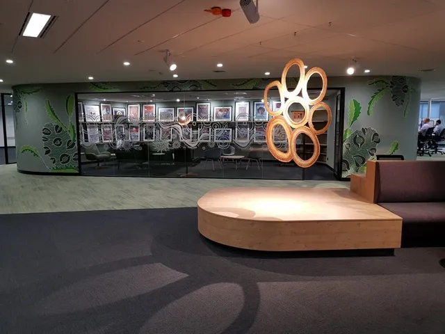 Green botanical mural, white line art glass decals, and a hanging ring sculpture in an office space