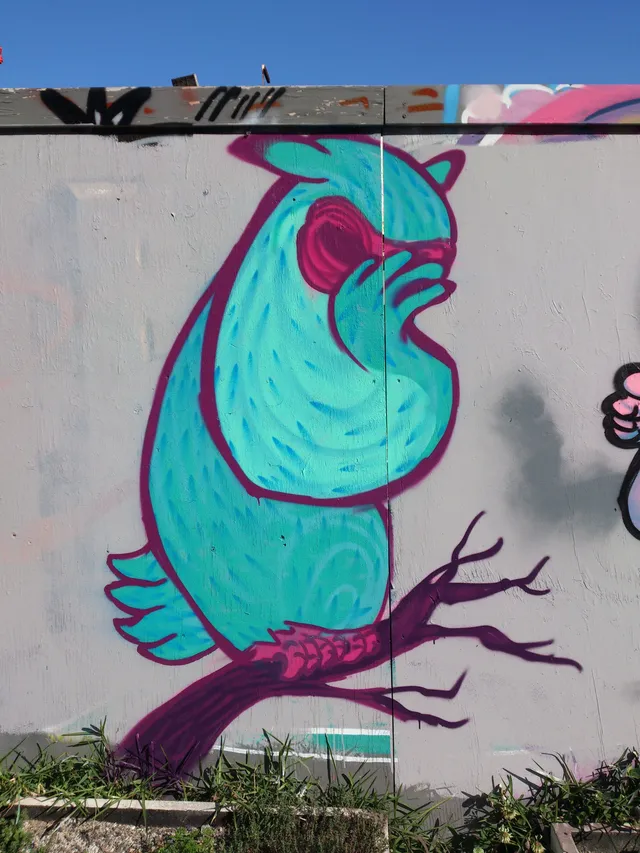 Mural of a stylized teal bird with bold magenta outlines perching on a branch and holding a wing over its face