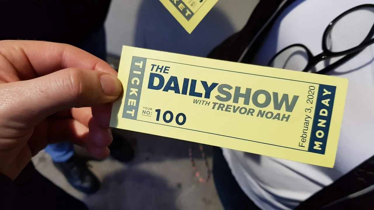 Hand holding a yellow ticket for The Daily Show with Trevor Noah, dated February 3, 2020, numbered 100