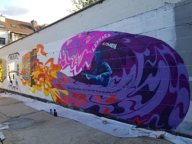 Brick wall mural of Leonard Cohen playing guitar inside a purple psychedelic swirl, connected to fiery orange waves