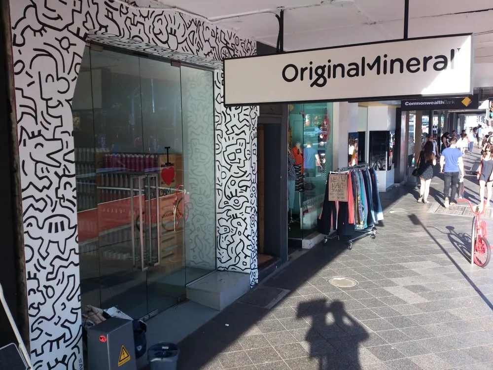 Black and white mural with bold line art of abstract shapes and characters framing a shop entrance