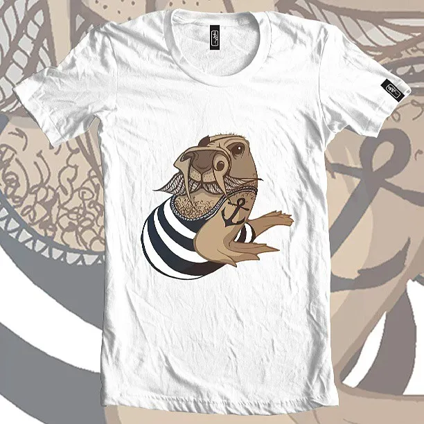 White t-shirt design featuring an illustration of a walrus in a striped sailor shirt with an anchor tattoo