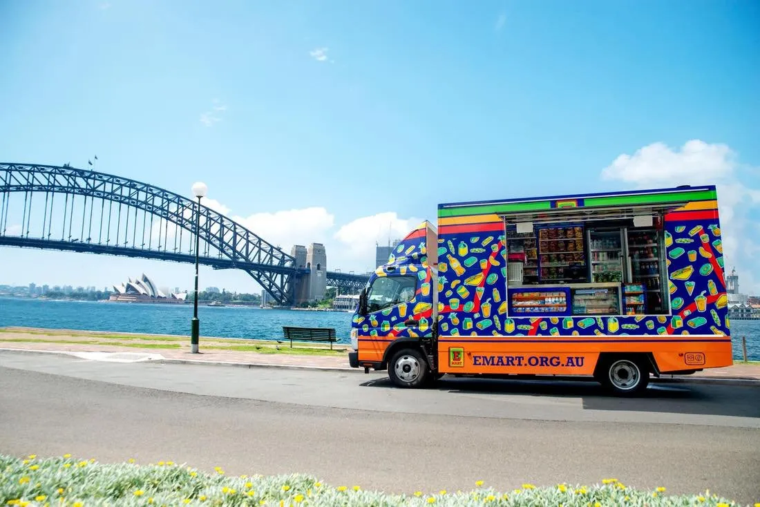 Mobile store truck painted with a bright, repeating illustration of food and drinks, parked near Sydney Harbour Bridge