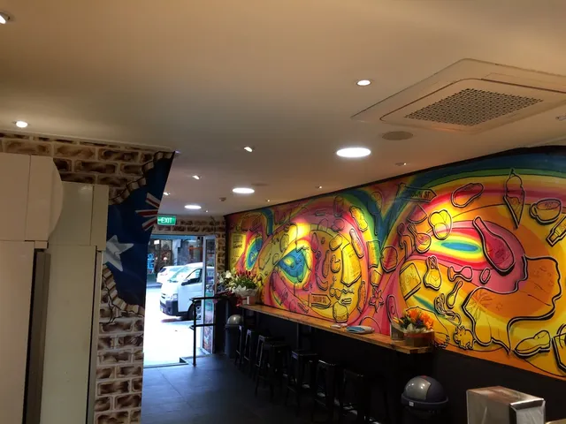 Vibrant indoor mural featuring a swirling psychedelic rainbow overlaid with bold line drawings of food items