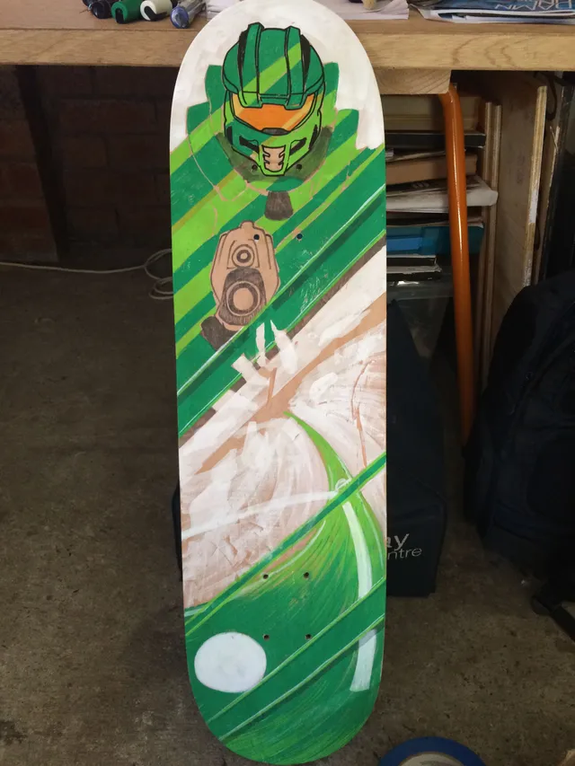 Hand-painted skateboard deck featuring a green armored sci-fi helmet and gun over diagonal green stripes