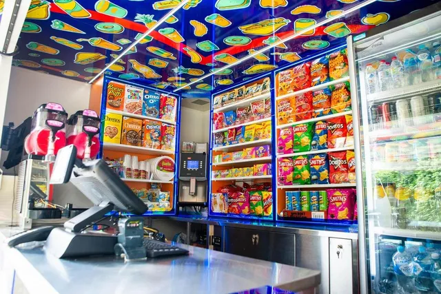Interior of a mobile snack store featuring a bright blue ceiling wrap illustrated with repeating food and drink motifs