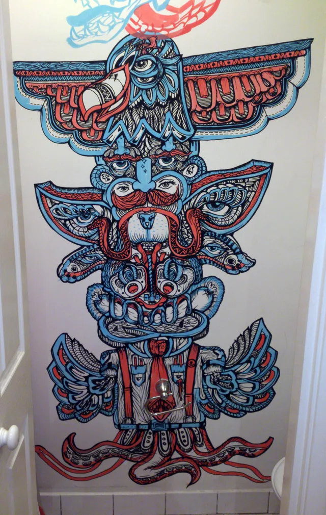 Psychedelic red and blue mural on a door showing a totemic stack of an eagle, surreal faces, and tentacles