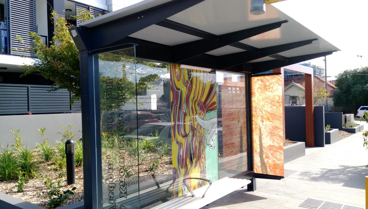 Vibrant psychedelic graphic of swirling lines and a reaching hand applied to the glass panels of a public bus shelter