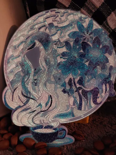 Glittery enamel pin depicting a coffee cup with swirling steam forming a woman's hair and large blue flowers