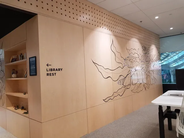 Black line art mural of tropical foliage on a light wood paneled office wall
