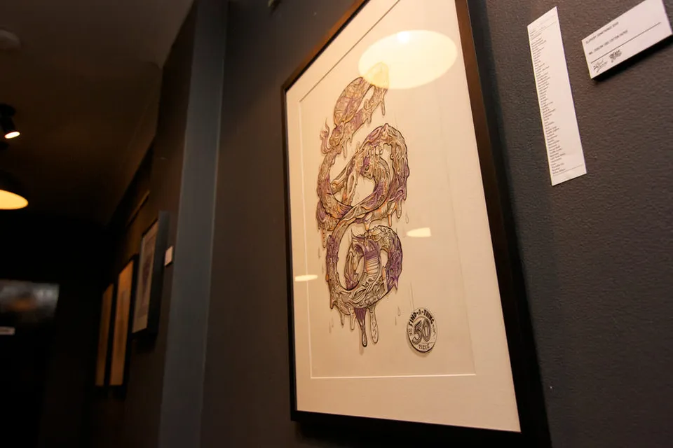 Framed drawing on a gallery wall featuring a psychedelic, melting serpentine shape in purple and gold line work