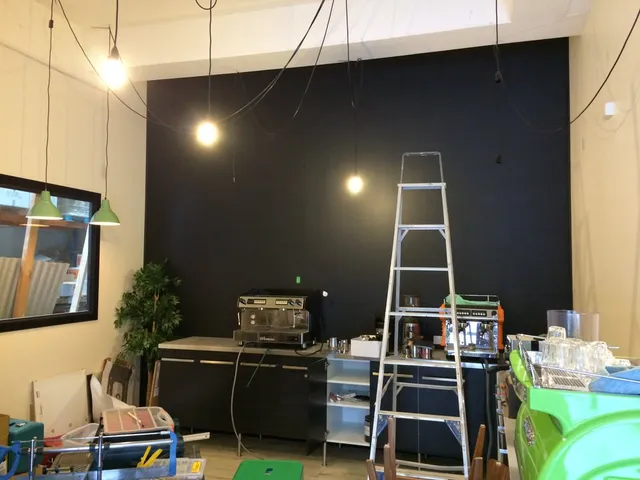 Blank black wall behind a coffee counter with a step ladder and espresso machines