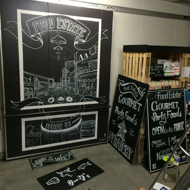 Chalkboard murals for Food Estate featuring a white line perspective drawing of a store aisle and hand-lettered signs