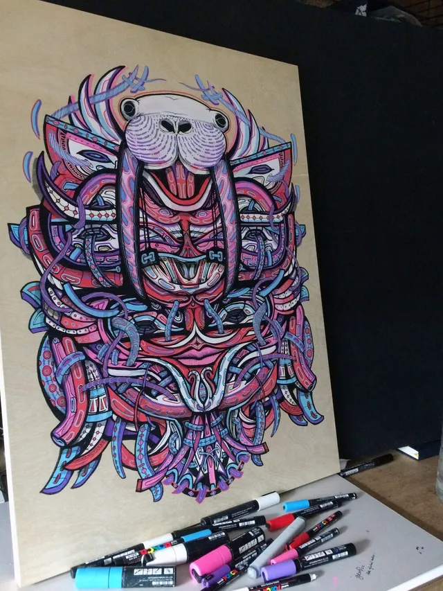 Psychedelic marker drawing on wood depicting a symmetrical, totemic walrus mask in pink and blue