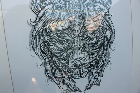 Intricate black ink drawing of a symmetrical face with multiple eyes and a crocodile mask