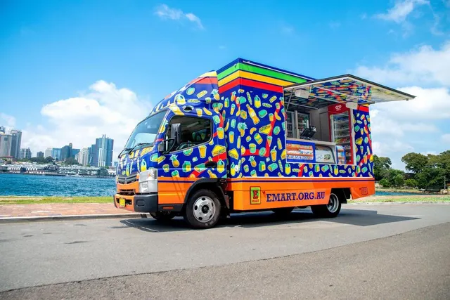 E-Mart truck featuring a vibrant vehicle wrap with repeating illustrated food and drink patterns on a blue background