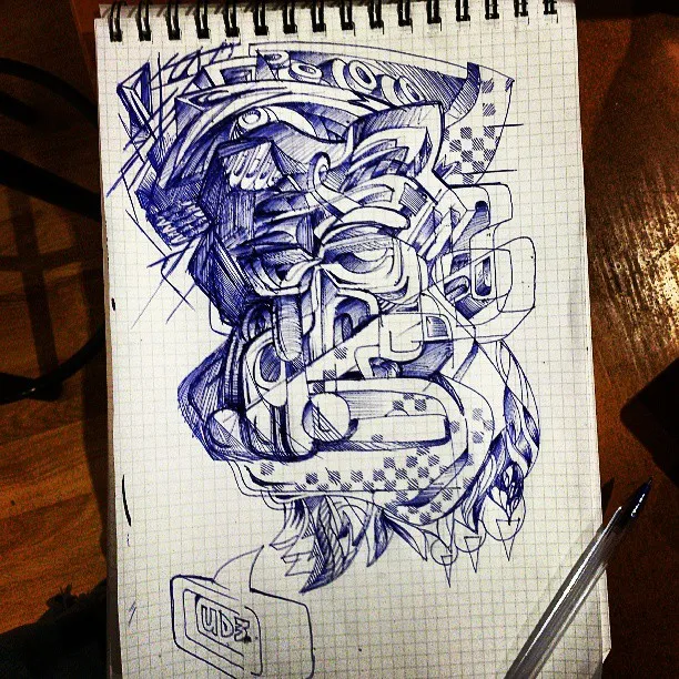 Blue pen sketch in a grid notebook of an abstract, psychedelic totemic face with bold geometric line work