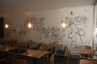 Cafe wall mural featuring bold black line art of a barista pouring coffee amidst abstract shapes