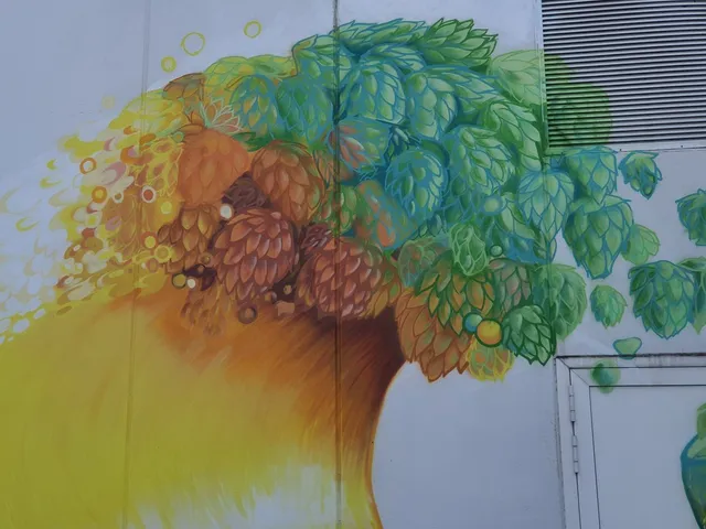 Mural on a white wall depicting a cluster of green and brown hops that blends into a flowing golden yellow wave