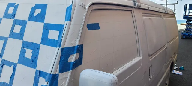 White van prepped for a mural with blue masking tape forming squares and grid lines drawn on the side panels