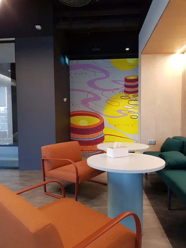 Colorful mural featuring pink swirls, yellow pools, and stacked patterned vessels in a modern office lounge