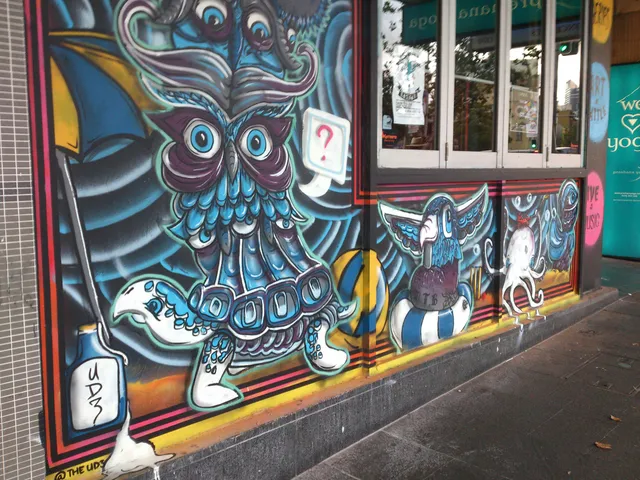 Street mural of a psychedelic blue owl creature with a question mark bubble beside an octopus and a bird in a life ring