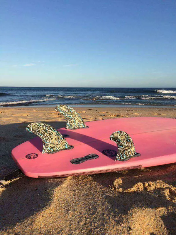 Finished surfboard fins installed in surfboard at the beach at sunset