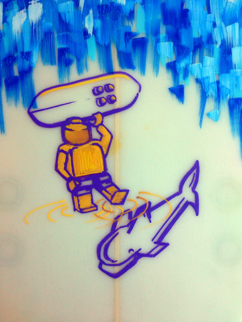Surfboard painting of a yellow Lego figure carrying a board above a purple shark outline and blue brushstrokes