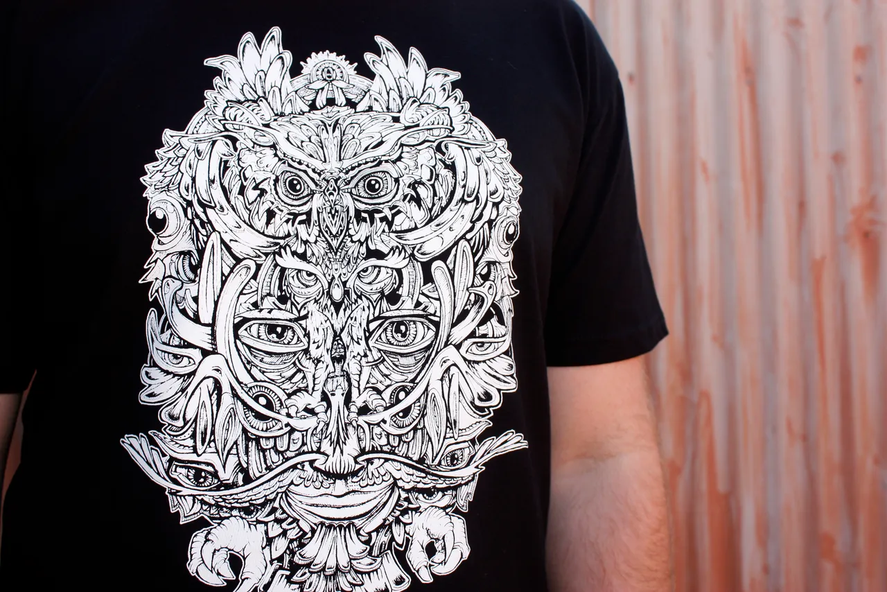 Black t-shirt with a white symmetrical line-art illustration of an owl and totemic face