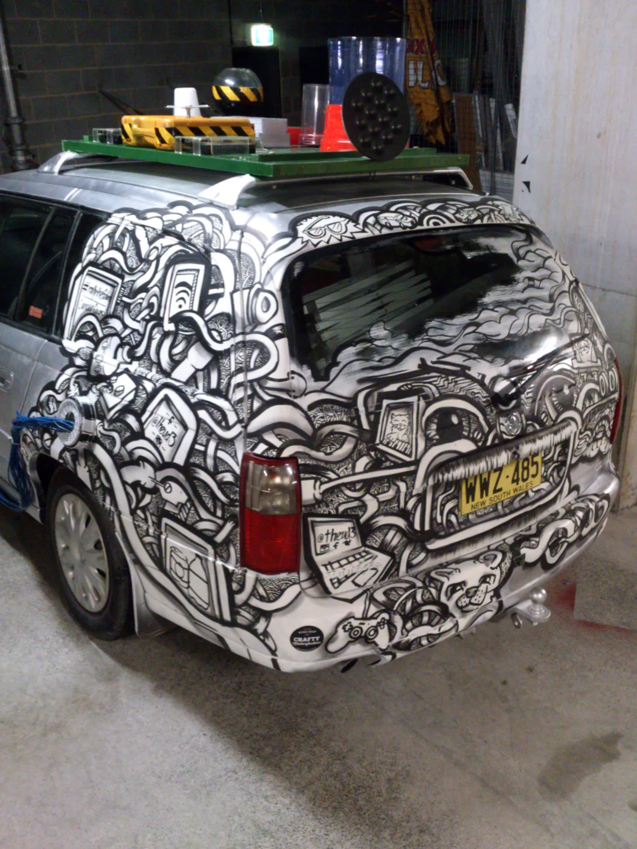 Custom-painted station wagon with dense black and white psychedelic designs of faces, tech, and lines