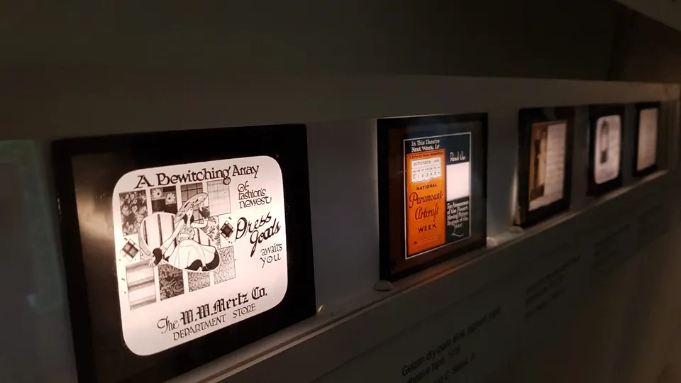 Framed vintage-style advertisements displayed in a row, featuring illustrated designs with bold typography and retro