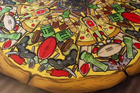 Colorful illustration of a pizza topped with chaotic party items like beer cans, game controllers, and footballs