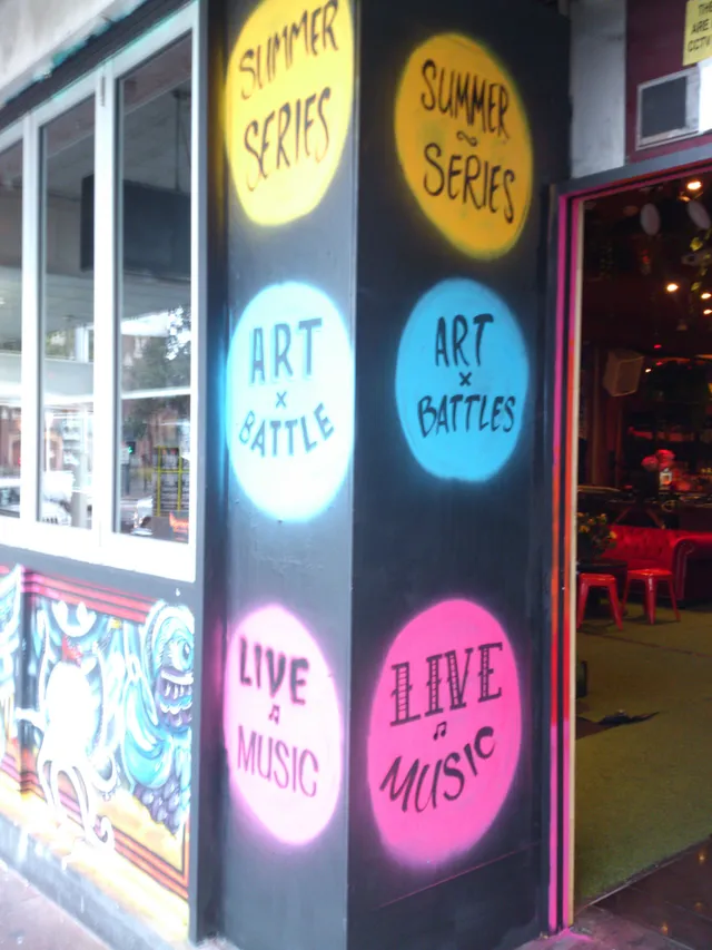 Spray-painted mural on a black pillar with colored circles reading Summer Series, Art Battles, and Live Music
