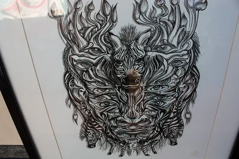 Symmetrical ink drawing of a psychedelic mask featuring a central zebra head embedded within layers of repeating eyes