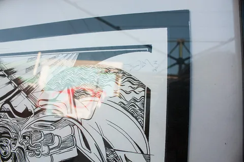 Framed abstract black and white ink drawing with bold lines and wavy patterns under reflective glass