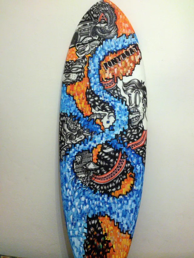 Hand-painted surfboard with blue and orange block patterns and bold black line art of faces and totemic creatures