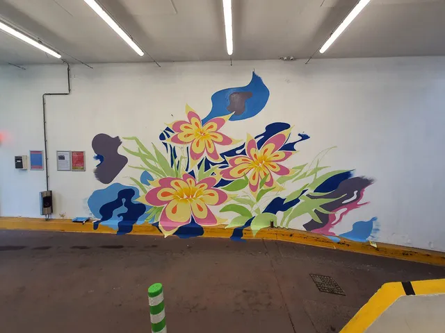 Mural on a carpark wall depicting three large pink and yellow flowers surrounded by abstract fluid blue shapes