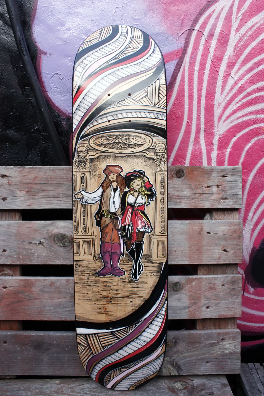 Painted skateboard deck depicting a pirate couple in an archway framed top and bottom by abstract swirling line work