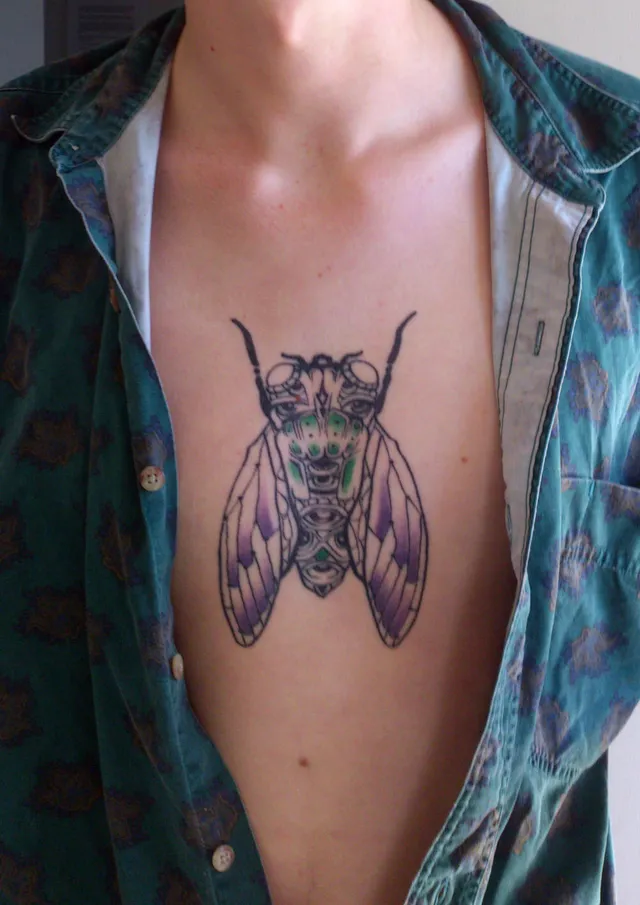 Symmetrical cicada chest tattoo with bold black linework, green body details and purple shading on the wings