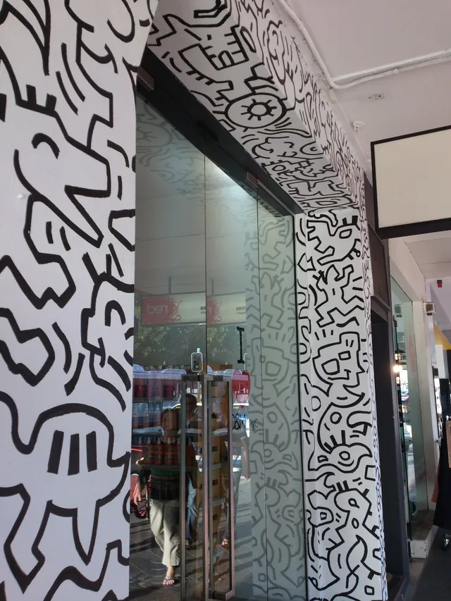 Black and white mural featuring bold, totemic line work framing a glass storefront entrance