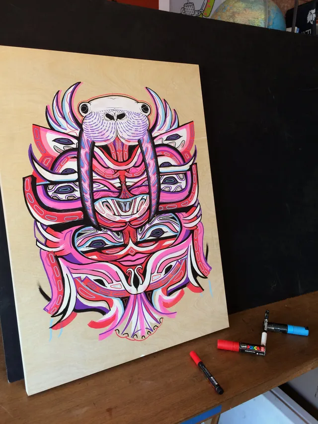Totemic pink and purple walrus mask and abstract symmetrical faces painted on a wooden panel