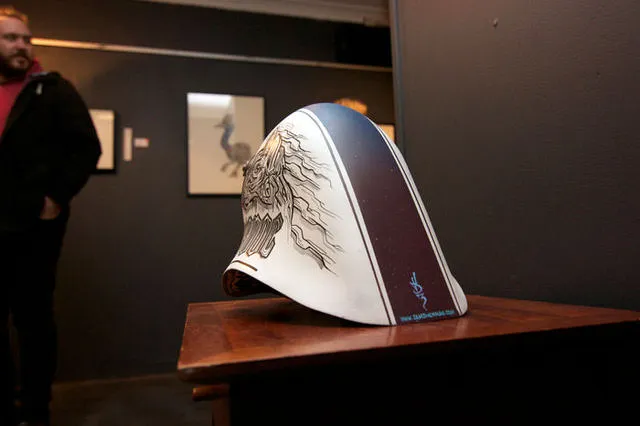 Hand-painted white helmet featuring a bold line drawing of a totemic face and a dark gradient center stripe