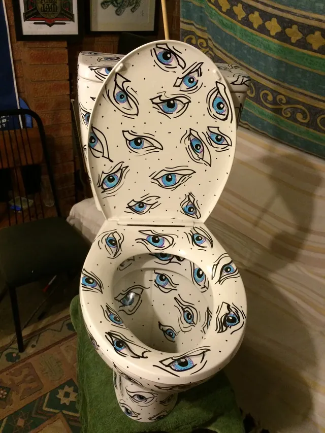 Hand-painted toilet covered in a psychedelic pattern of stylized blue eyes with bold black outlines
