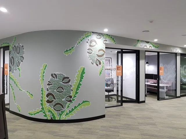 Mural on a curved office wall depicting bold, stylized banksia flowers and jagged green leaves