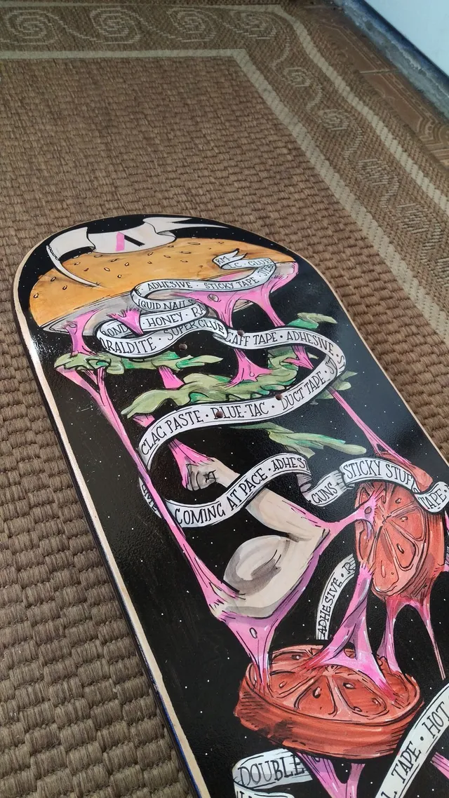 Painted skateboard featuring a surreal deconstructed burger, stretching pink slime, a muscular arm, and text ribbons