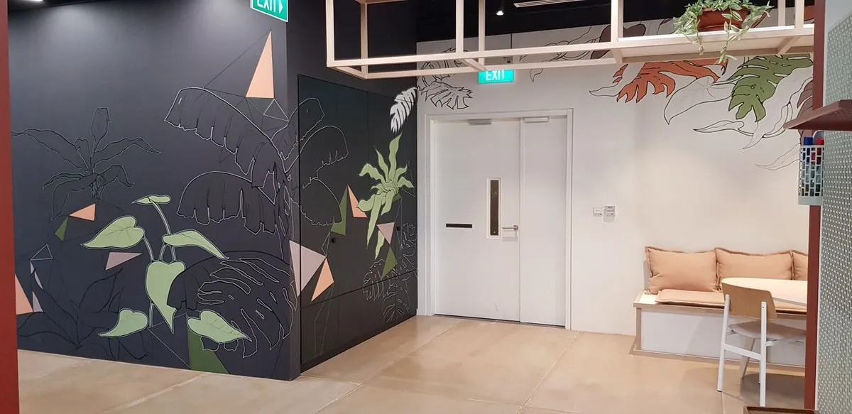 Interior mural featuring bold outlines of tropical leaves and geometric shapes on dark and white walls