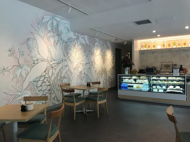 Botanical wall mural featuring large leaves and pastel floral line work in a cafe interior