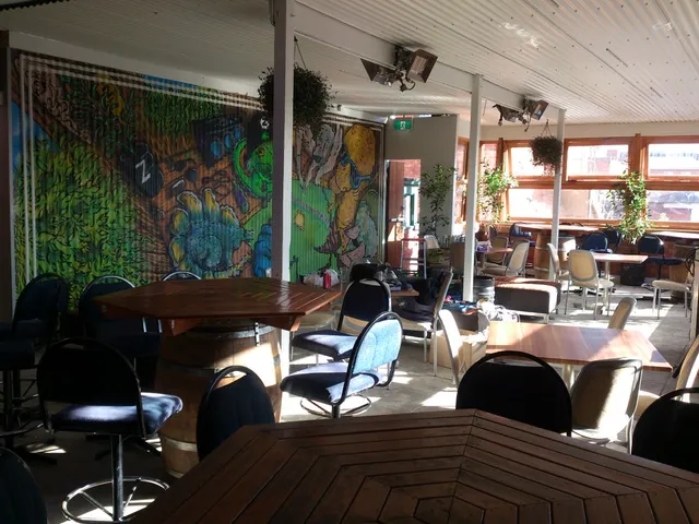 Colorful mural featuring psychedelic green and yellow designs painted on a corrugated wall inside a bar